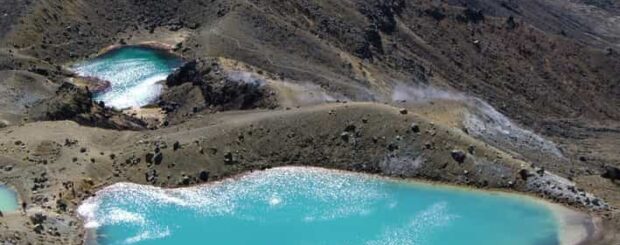 Scenic view of the Tongariro Alpine Crossing trail, featuring volcanic landscapes, emerald lakes, and rugged mountain terrain.