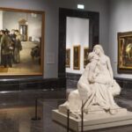 Neoclassical facade of the Prado Museum with a group of tourists waiting for a guided tour